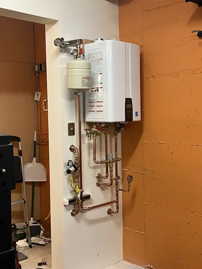 Plumbing technician inspecting water heater connections in Oshtemo